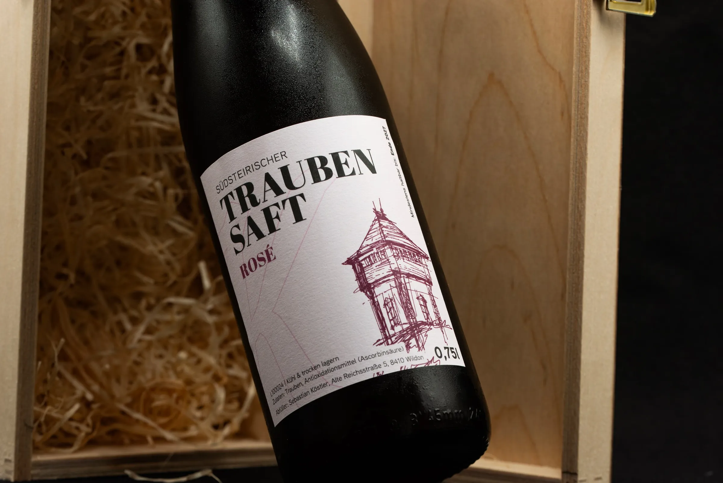 Flasche Traubensaft Rosé in einer Holzkiste mit Holzwolle